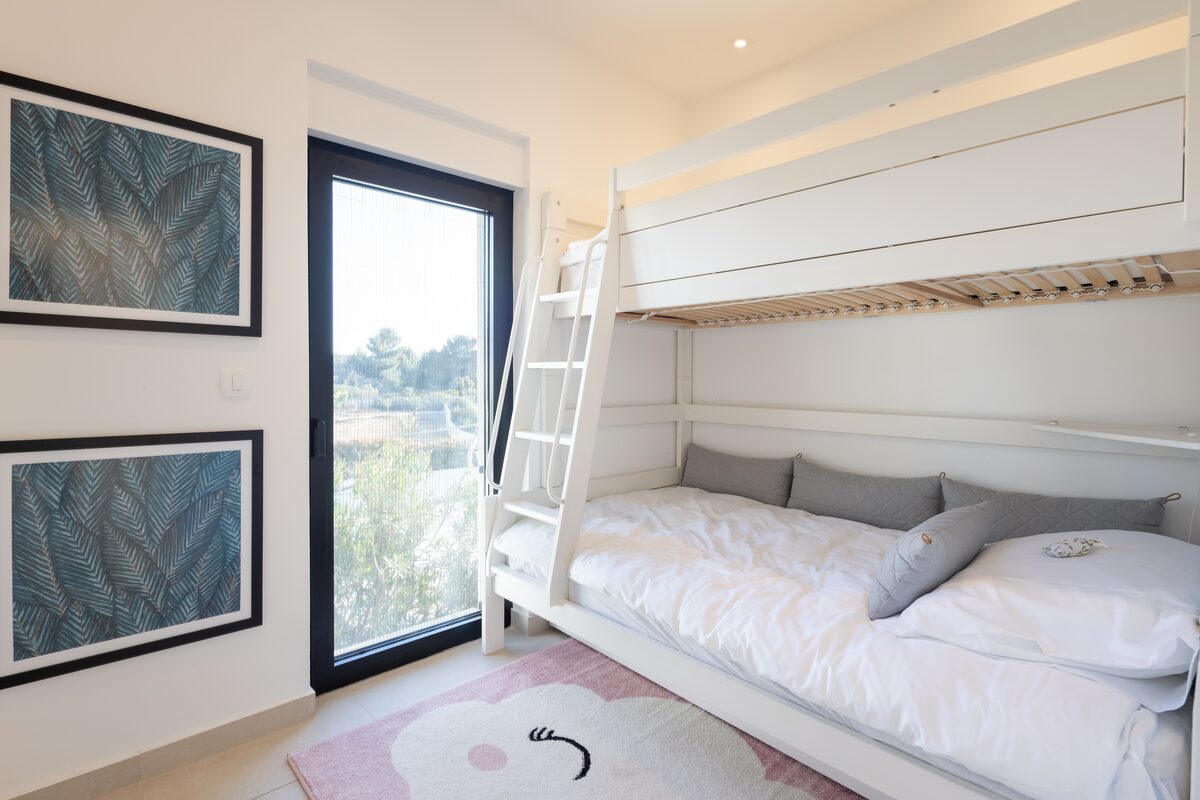 Bunk room with built-in white bunk bed, teal palm prints and a pink rug