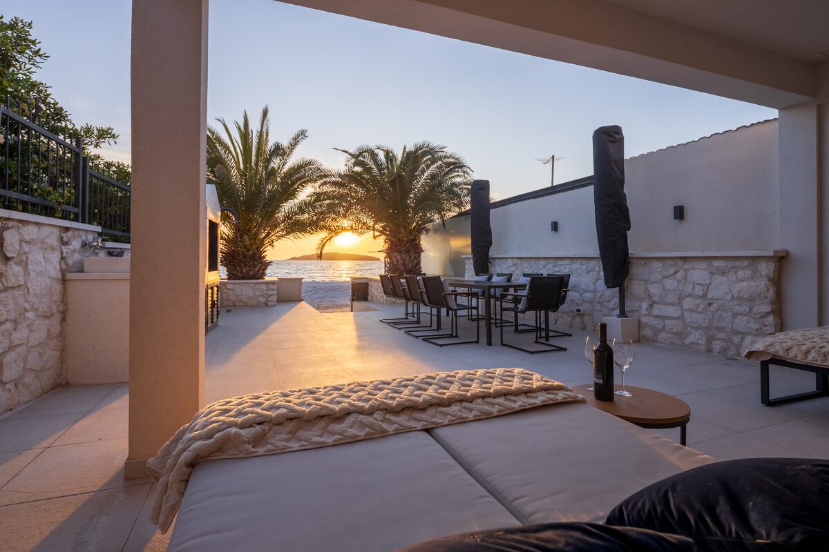 Outdoor kitchen with built-in fireplace, stone counter, sink and louvred cabinetry concealing an outdoor fridge