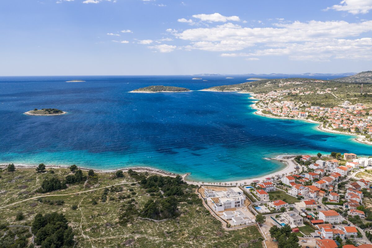 Aerial view of Rogoznica bay showing the white pebble beach and turquoise shallows